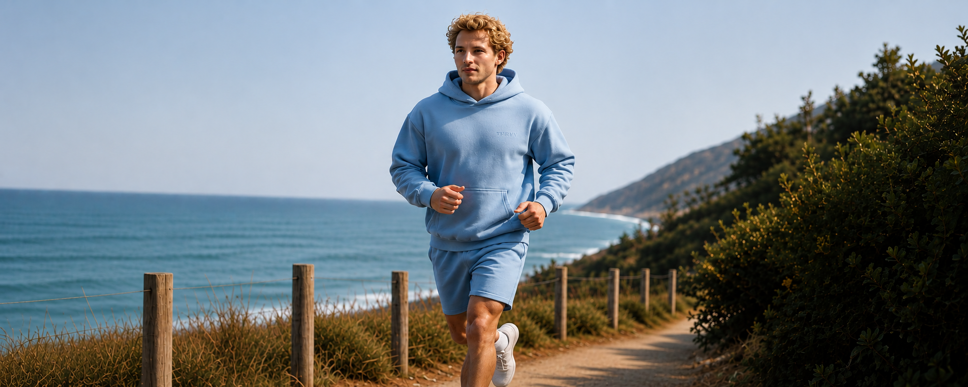 Runner on a coastal path wearing a Thryv sweatshirt at sunrise